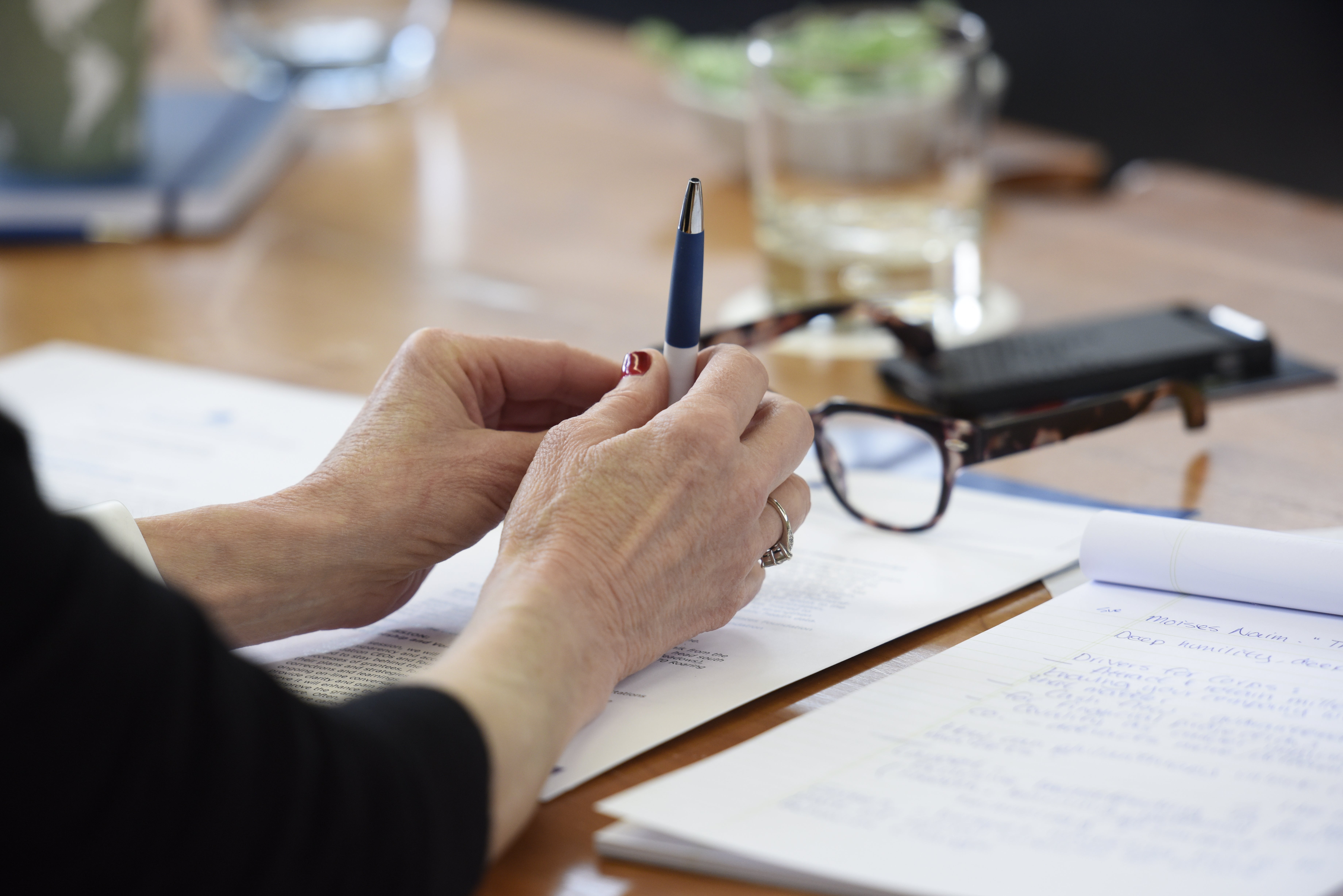 Woman's hands holding a pen on a desk