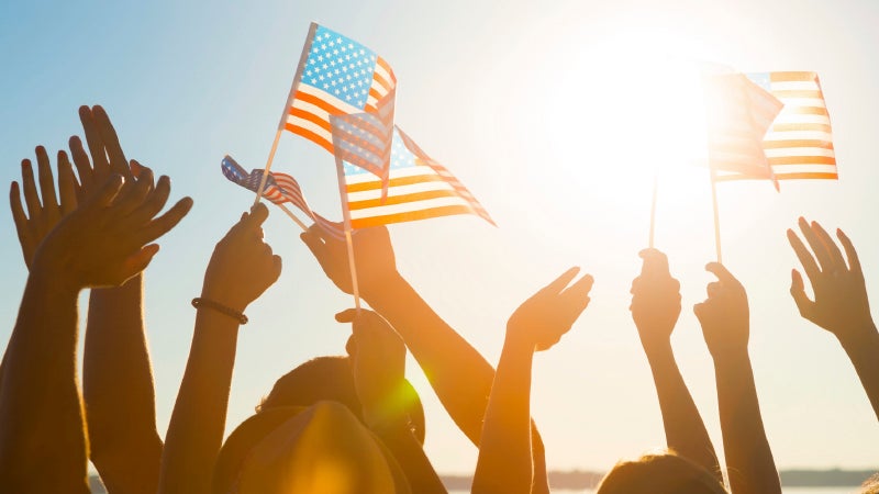 Hands reaching up holding American flags