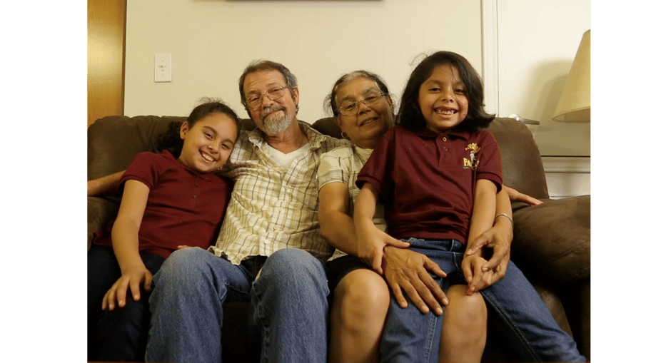 Family of four smiling and sitting together on the couch