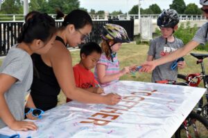Adult and children signing a poster with the word "together"