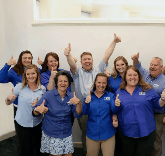 Work team smiling and giving camera two thumbs up