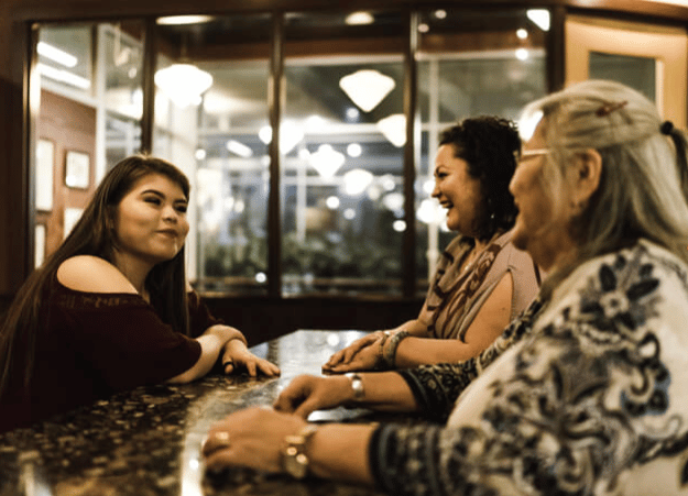 Three Indigenous women sit around a table