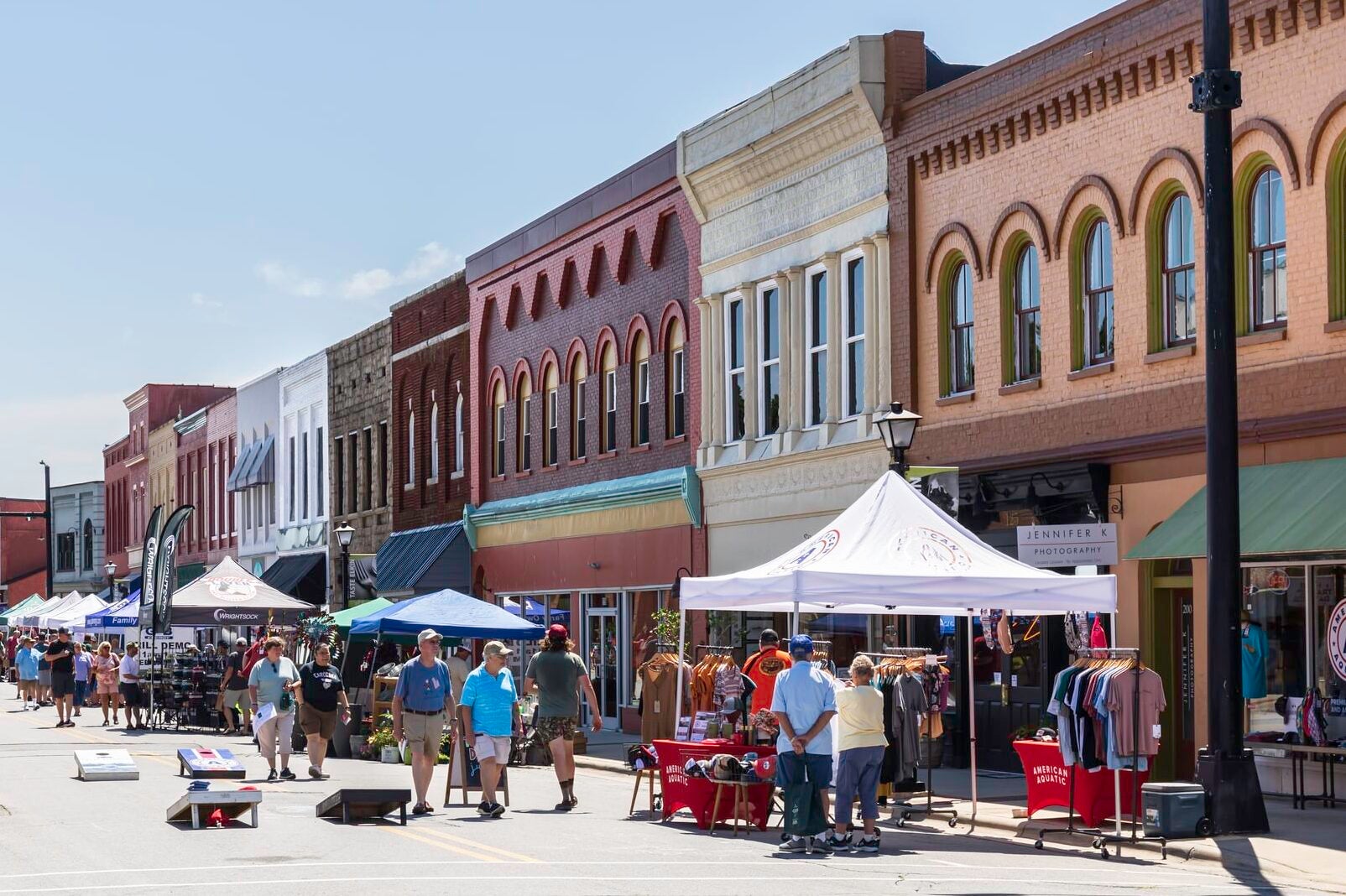 A summer street festival, with vendors under canopies on a hot day.