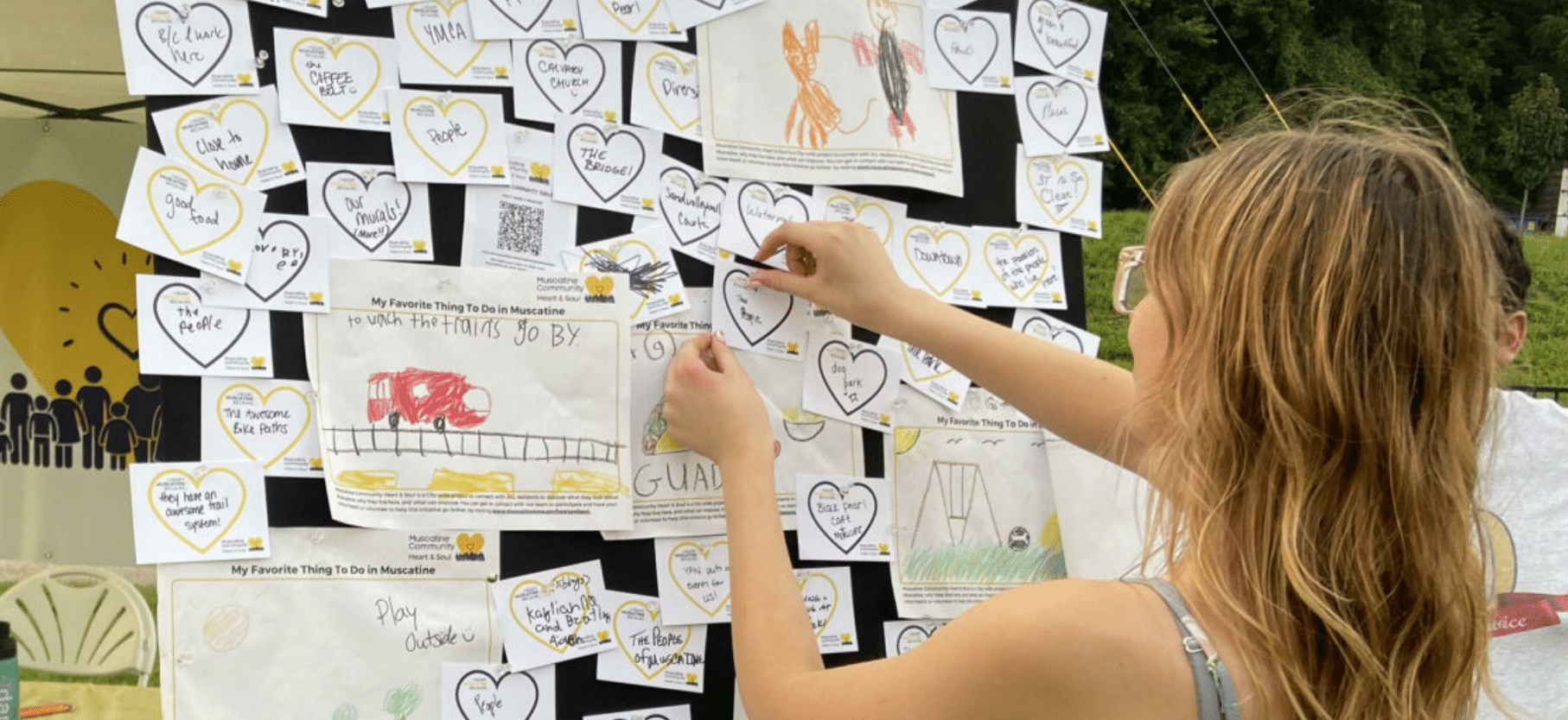Grade-school age child putting up encouraging notes outside on bulletin board