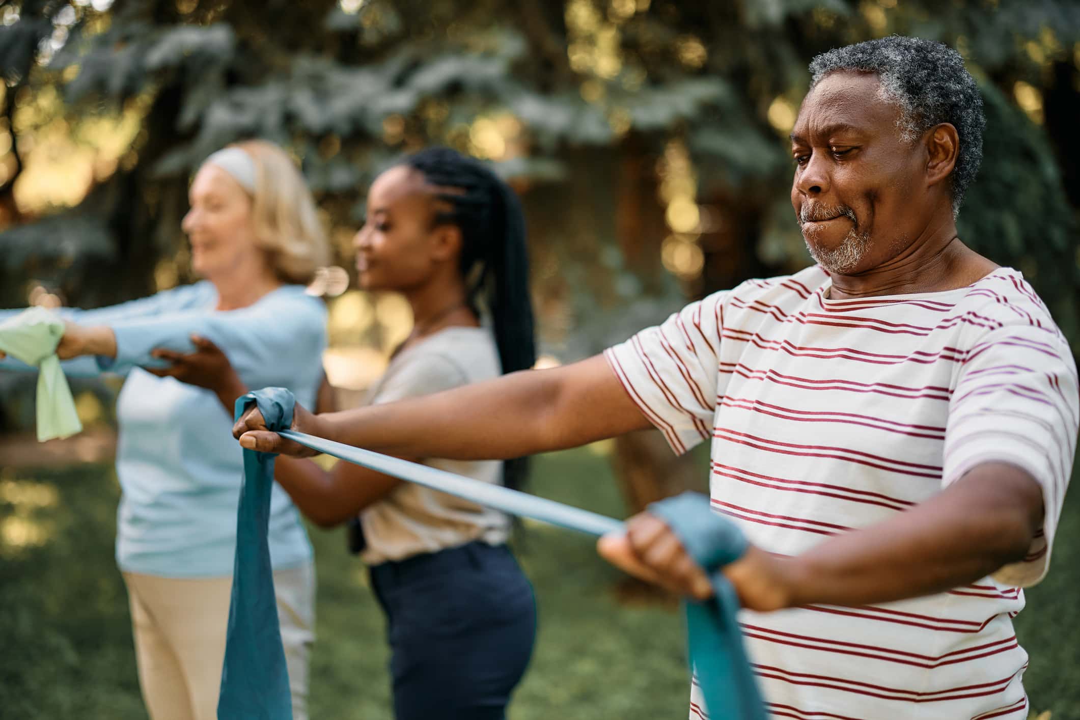 African American man practicing with power band on exercise class in nature.