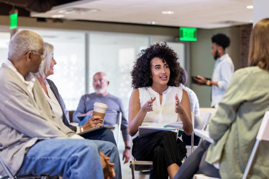 During a community meeting, an adult woman uses gestures to emphasize her point.