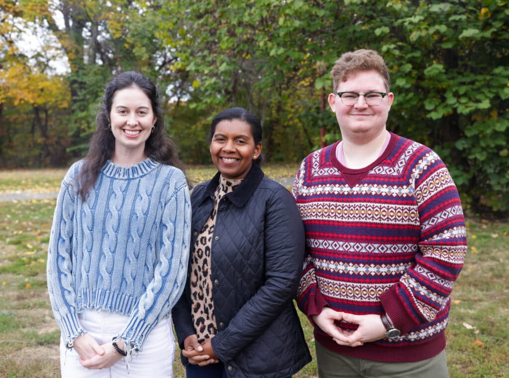 The Aspen CSG team pose outside in front of trees in fall sweaters