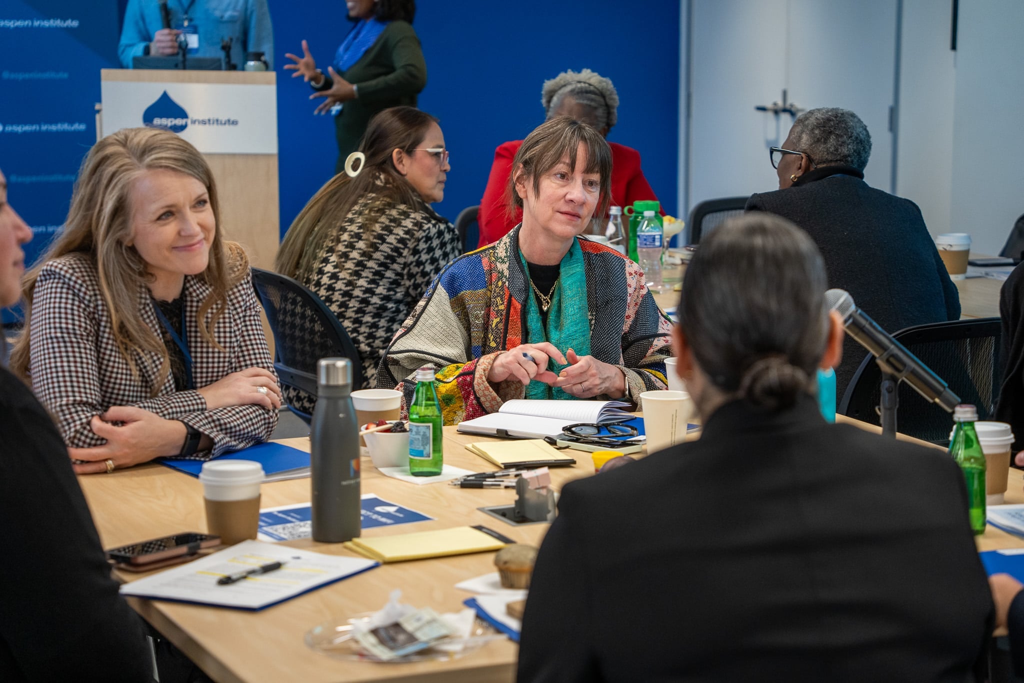 Group of rural development leaders sit talking around a table.
